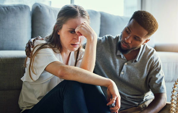 Image of black man comforting distressed white woman